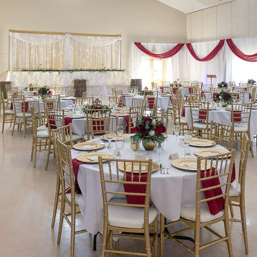 room with organza backdrop behind head table, and table settings