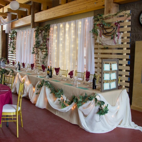 head table with organza backdrop, lights, and wooden slat sections