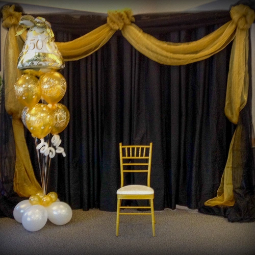 gold and white balloon bouquet beside chiavari chair for 50th