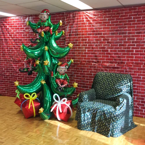foil balloon Christmas tree and presents beside Santa