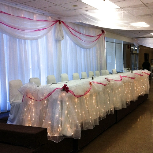 head table with lights and burgundy ribbon draping