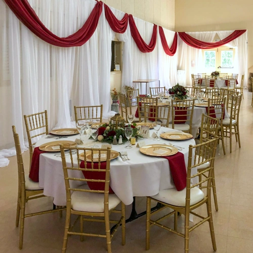 round tables with chiavari chairs, organza backdrop and burgundy draping