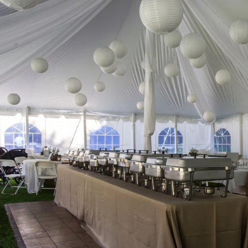 organza tent decor with hanging balls, and chafing dishes on buffet table