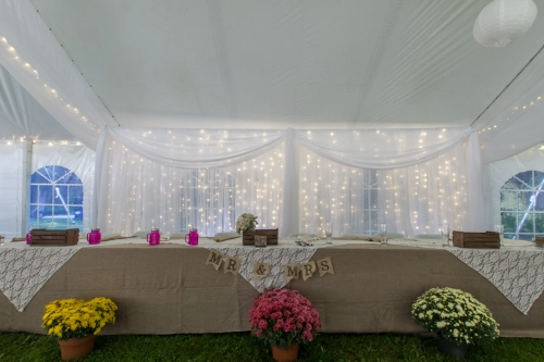 white organza backdrop with white mini lights, head table with burlap  cloth and lace overlays