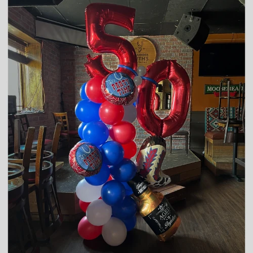 50th birthday sculpture in red, white, and blue balloons with foil numbers, cowboy boot, and whiskey bottle