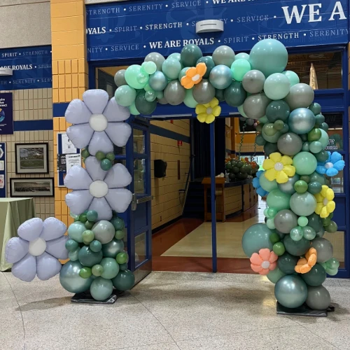 an arch for spring with different shades of green balloons and balloon flowers