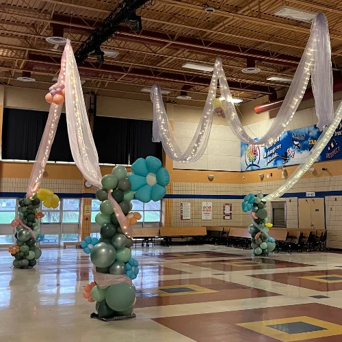 spring dance decor with flower columns and fairy lights in organza ceiling swags