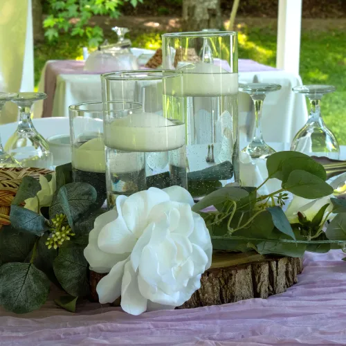 Wedding centrepiece with wood slab base and 3 sizes of glass cylinders with candles