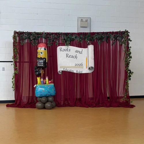 backdrop for Education Gala with burgundy organza and school supplies balloons