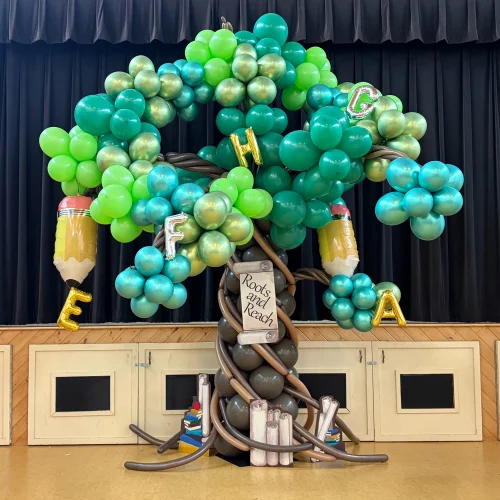 balloon sculpture of a tree for Education Gala with theme "Roots and Reach". Books, mylar letters and pencils
