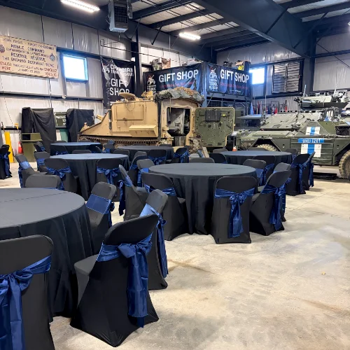 tables and chairs with black linen and royal blue bows for event at Canadian Tank Museum in Oshawa